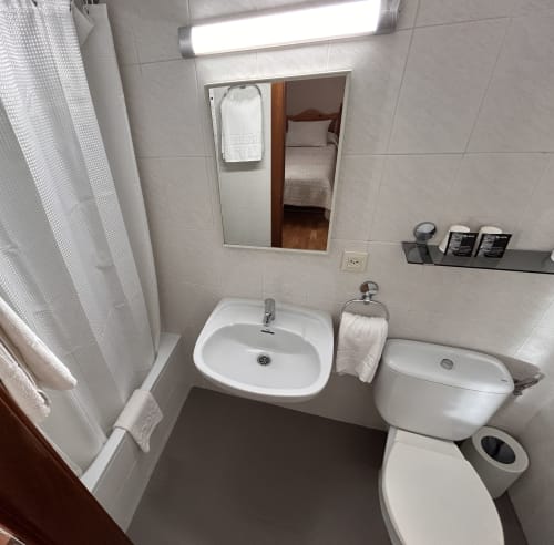 Clean bathroom at Hostal Estació in Puigcerdà with sink, toilet, shower, towel rack and mirror