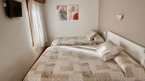 Triple bedroom at Hostal Estació in Puigcerdà with two beds, mountain views, TV, and modern décor