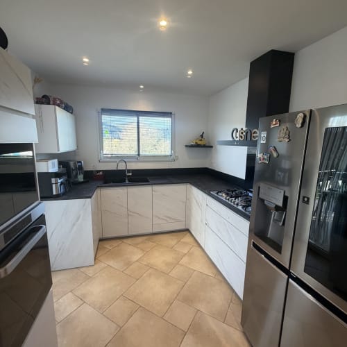 Cuisine moderne avec meubles blancs, plan de travail noir, électroménagers inox au Gîte la Villa des Falaises du Lot