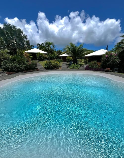 Piscine circulaire cristalline aux Cottages du Lagon, Saint-François, Guadeloupe, avec parasols blancs et jardins tropicaux