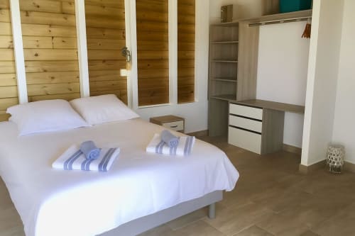 Chambre moderne aux Cottages du Lagon, Saint-François avec lit, oreillers blancs, serviettes rayées et armoire en bois