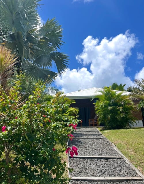 Bungalow tropical aux Cottages du Lagon à Saint-François avec palmiers, fleurs roses et ciel bleu éclatant
