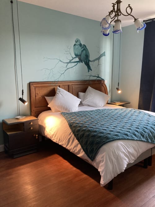 The Les Inséparables bed and breakfast at Clos d'Azel features a wooden headboard made from an old walnut door, a hand-painted mural of lovebirds, pendant lights from the Nancy school, and a garden with a heated swimming pool.