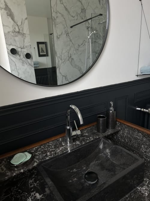 Modern bathroom with black marble sink, authentic marble vanity unit, and modern round mirror at Clos d'Azel in Alsace