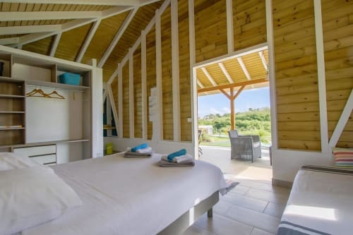 Bright cottage bedroom at Cottages du Lagon in Saint-François with wooden beams, pool view terrace, and modern furnishings