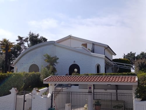 Casa moderna con muri bianchi e architettura curvilinea, tetto in cotto, situata ad Ancona con ingresso cancellato