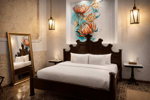 Elegant bedroom at Villa Merida Boutique Hotel with dark wood bed, white linens, and floral artwork above headboard in