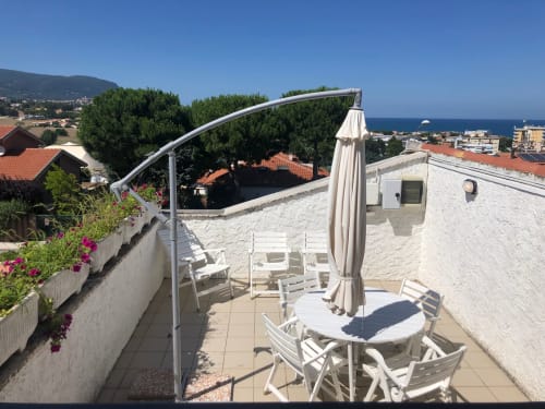 Terrazza soleggiata con vista mare ad Ancona, lettini bianchi, ombrellone e fiori rosa - Casa Alimento