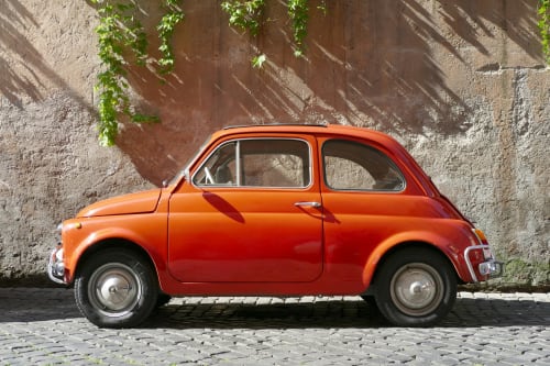 Vintage red Fiat 500 parked in Crémieu, charming backdrop for Le Clos Ayanna B&B