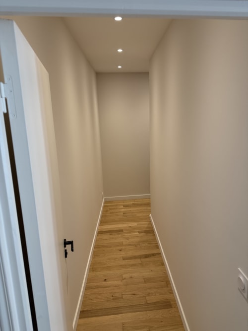 Couloir moderne avec parquet et murs couleur crème dans un appartement rénové d'Antibes