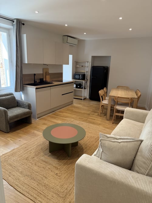 Appartement moderne ouvert à Antibes avec cuisine crème, table à manger, parquet et coin salon confortable