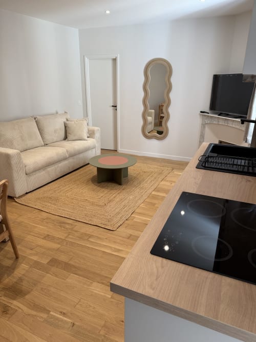 Cuisine ouverte moderne et séjour dans appartement à Antibes avec canapé beige, plan de travail en bois, plaque à induction
