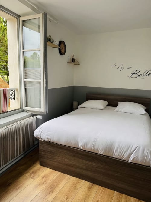 Chambre moderne du Relais Saint-Laurent à Chevreuse avec lit queen-size, mur d'accent sombre et vue sur le jardin