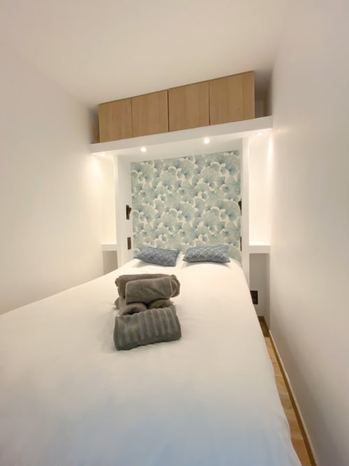 Chambre moderne aux Hébergements C&C à Angres avec tête de lit intégrée, éclairage ambiant, papier peint à motifs et serviettes pliées