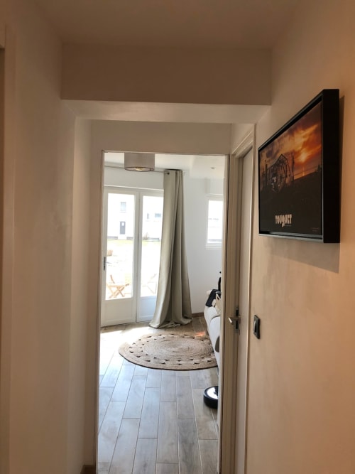 Couloir du studio aux Hébergements C&C à Angres avec sol carrelé, porte ouverte sur la terrasse, TV murale et style moderne