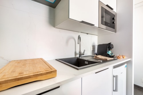 Cuisine moderne de l'appartement Le Cocon aux Hébergements C&C, Angres avec meubles blancs, évier noir et planche à découper en bois