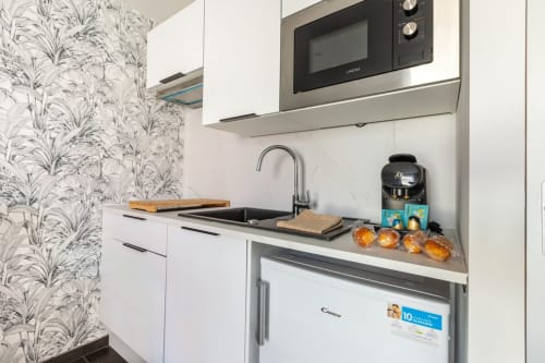 Kitchenette moderne de l'appartement Le Cocon aux Hébergements C&C : mobilier blanc, machine Nespresso et équipements inox