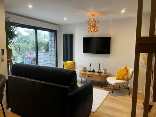 Séjour contemporain aux Hébergements C&C à Angres : canapé noir, touches jaunes, TV murale, vue jardin