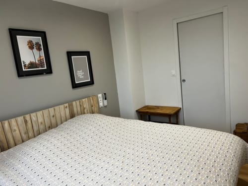 Chambre moderne aux Hébergements C&C à Angres avec lit à tête de lit en bois, tableaux encadrés et porte blanche