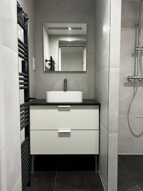 Salle de bain moderne avec vasque blanche, miroir encadré, porte-serviettes noir et douche à Hébergements C&C