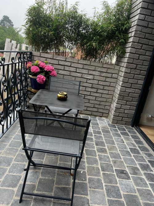 Patio privé d'Hébergements C&C à Angres avec table à manger, fleurs roses et murs en brique