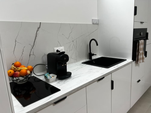 Cuisine moderne avec plan de travail en marbre, évier noir, cafetière Nespresso et corbeille de fruits à l'appartement C&C Angres