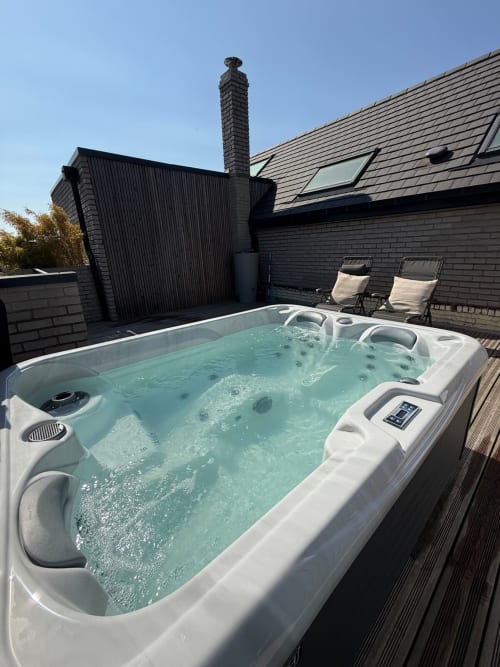 Jacuzzi chauffé en terrasse sur le toit d'Hébergements C&C, Angres, avec chaises longues et bâtiment moderne noir