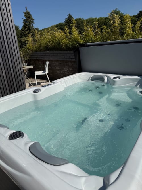 Jacuzzi chauffé sur la terrasse du toit des Hébergements C&C à Angres, avec chaise longue et vue sur la forêt