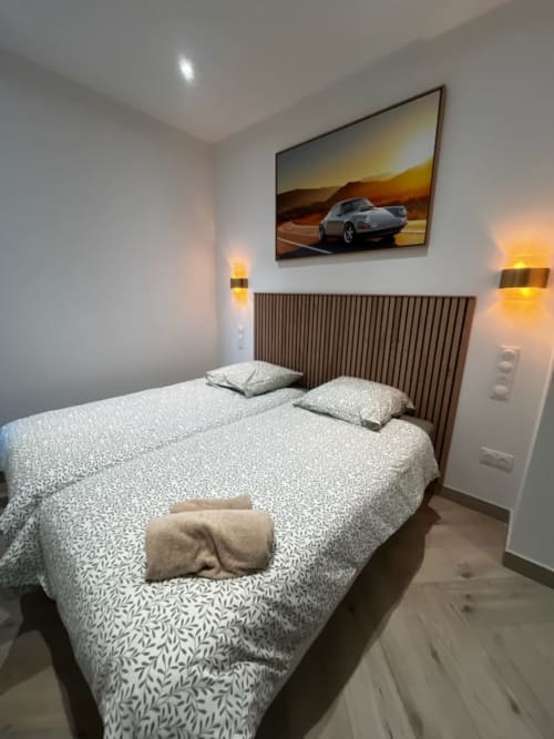 Chambre moderne aux Hébergements C&C à Angres : literie à motifs, tête de lit rayée, appliques murales et tableau de voiture de sport