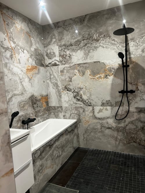 Salle de bains moderne de l'appartement Chez mamie aux Hébergements C&C avec carrelage effet marbre, robinetterie noire et douche italienne