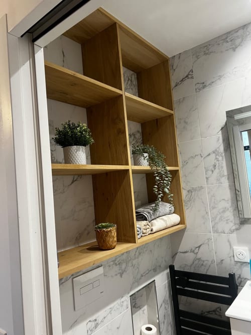 Étagère en bois dans la salle de bain de Chez mamie avec plantes en pot, serviettes roulées et articles de toilette