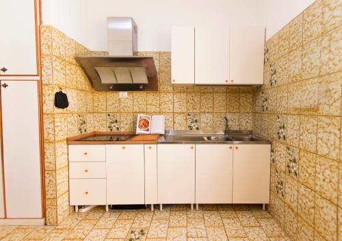 Cucina con mobili color crema, piano di lavoro in legno e piastrelle gialle decorate alla Roma Magic Flat di Roma