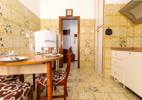 Cucina con piastrelle gialle, tavolo da pranzo in legno, elettrodomestici bianchi e pavimento decorativo presso Roma Magic Flat a Roma