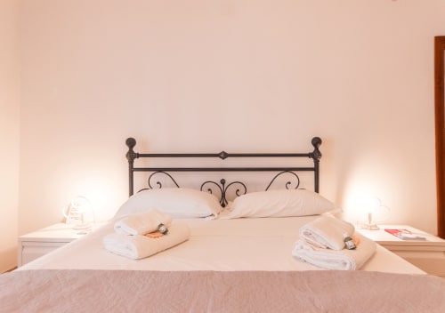 Elegante camera da letto al Roma Magic Flat con testata in ferro battuto, cuscini morbidi e asciugamani bianchi sul letto a Roma