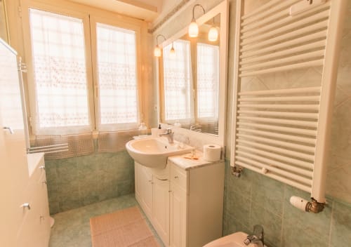Luminoso bagno di Roma Magic Flat con piastrelle verdi, lavabo bianco, doccia e scaldasalviette