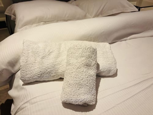 White rolled towels arranged on a bed at England Furnished Homes in High Wycombe