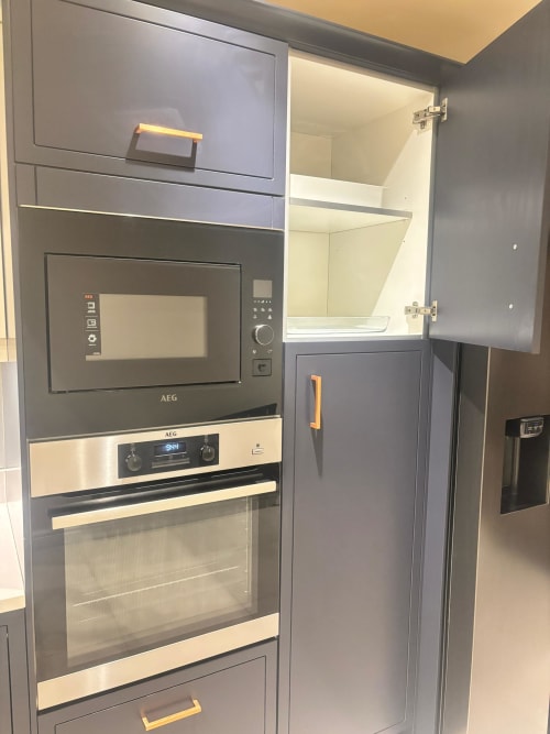 Modern kitchen with built-in AEG appliances, microwave, oven, and open cabinet in furnished home at England Furnished Homes,