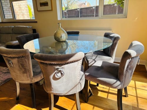 Modern dining room with glass table and upholstered chairs, garden view windows, yellow walls at England Furnished Homes in