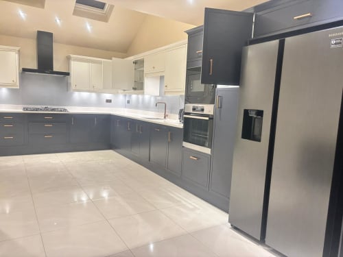 Modern kitchen with grey and cream cabinets, stainless steel appliances, white tile flooring, and granite countertops in a