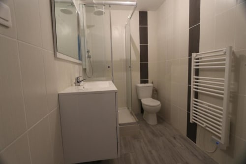 Salle de bains moderne du studio Appart'Hôtel avec lavabo, toilettes, douche, sèche-serviettes chauffant et carrelage