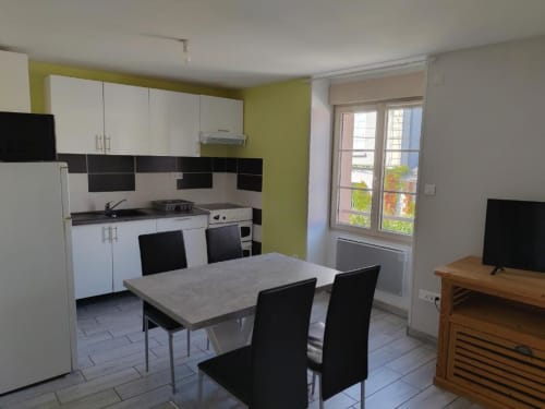 Cuisine et coin repas du studio à l'Appart'Hôtel Cholet avec mobilier blanc, table à manger et accès à la terrasse