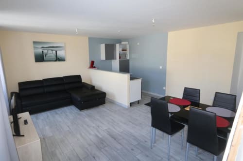 Studio moderne à l'Appart'Hôtel de Cholet avec canapé sectionnel noir, table à manger, kitchenette et bois clair