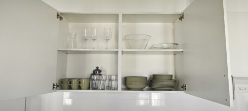 Armarios de cocina abiertos en apartamento Barcelona Eixample mostrando cristalería, platos y cuencos