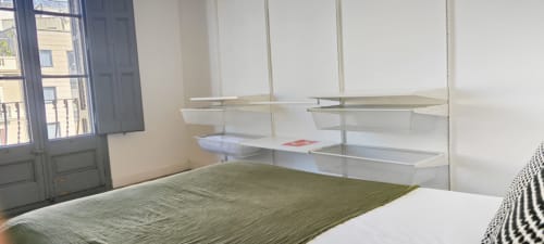Moderno dormitorio en apartamento del Eixample de Barcelona con vistas a la ciudad, cama verde y estantes minimalistas