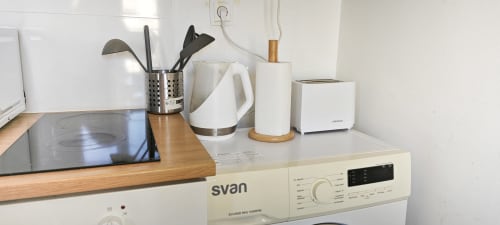 Moderna encimera de cocina en apartamento de Barcelona con electrodomésticos, soporte de utensilios y hervidor