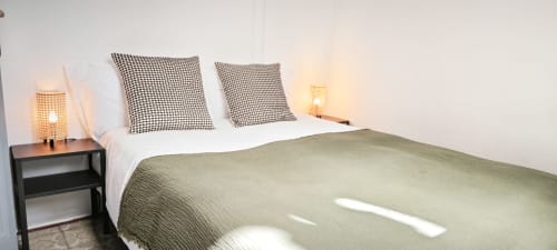 Dormitorio moderno en apartamento BCNMADflats Barcelona Eixample con cama matrimonial, almohadas estampadas y lámparas de mesita de noche