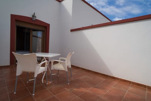 Sunny terrace with white chairs and table at Alojamientos Carolina y Vanesa in Níjar, Spain