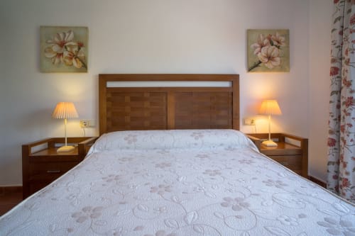 Cozy bedroom at Alojamientos Carolina y Vanesa in San José, Níjar with wooden bed frame, white quilted bedding, and warm