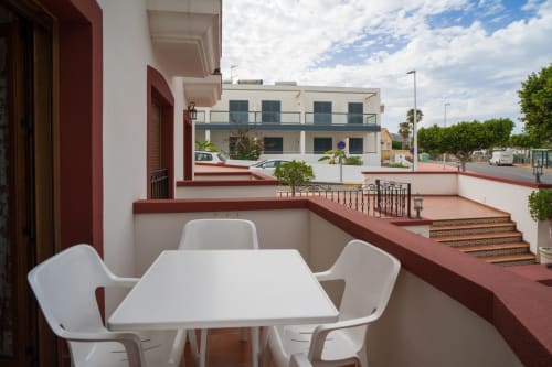 Terrace with white table and chairs at Alojamientos Carolina y Vanesa, Níjar, overlooking city with red-trimmed buildings