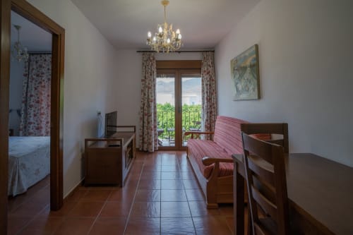 Bright apartment bedroom with wooden furniture, terracotta tiles, and city views in San José, Níjar